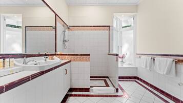 A modern bathroom with two sinks, a shower, and a bathtub.