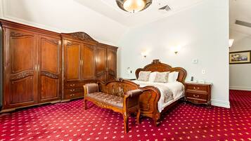 Une chambre à coucher avec une grande armoire en bois, un lit en bois doté d’une tête de lit et un tapis rouge à motifs.