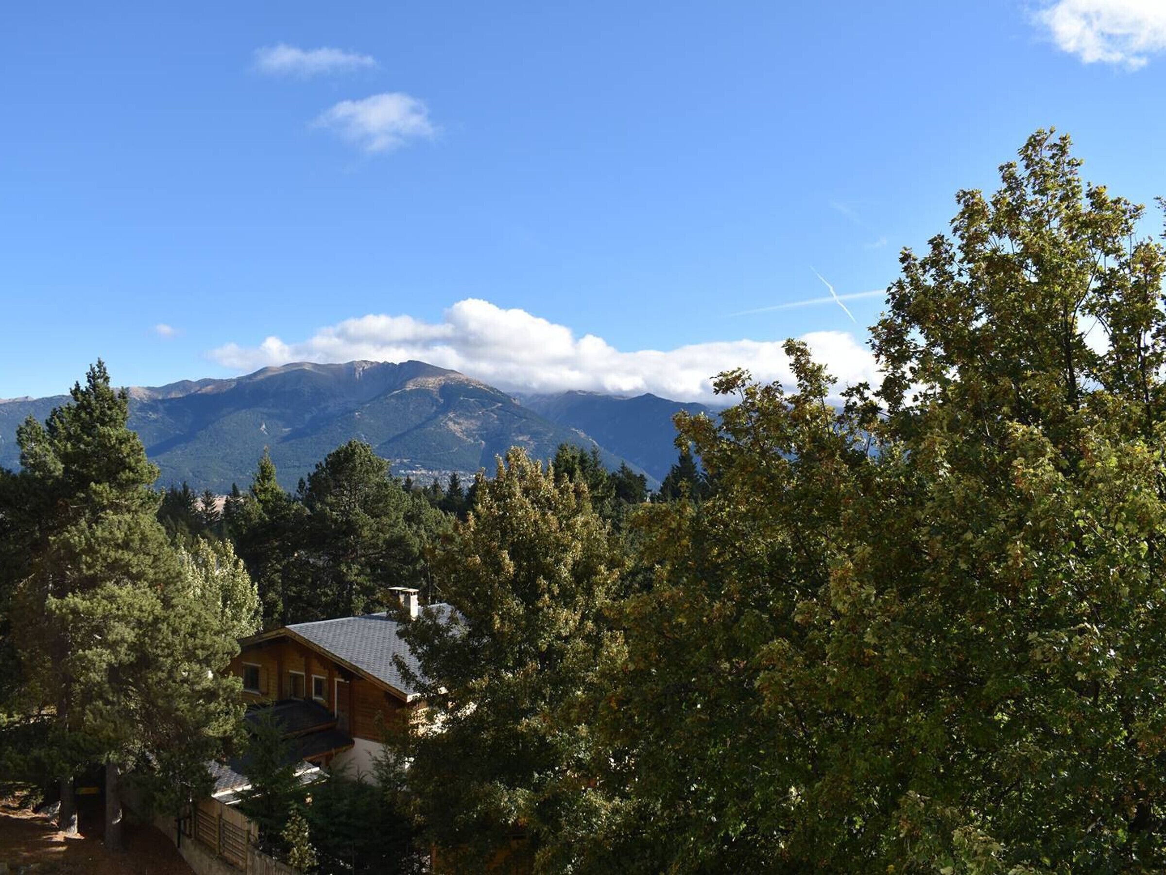 A mountain landscape with a house in the foreground.