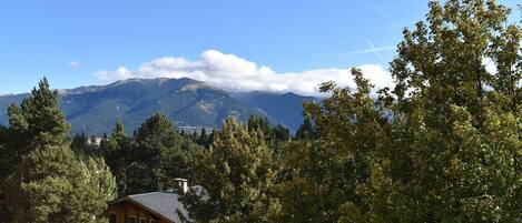 A mountain landscape with a house in the foreground.