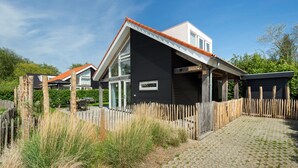 Ein modernes Haus mit schwarzer Fassade, einem geneigten Dach und einem Holzzaun.