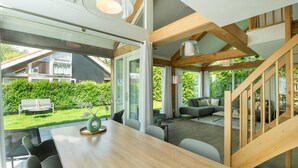 Ein modernes Interieur mit einem Holztisch, Stühlen, einer Couch und einer Treppe.