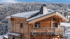 Un chalet in legno con un balcone, sullo sfondo di una montagna innevata.