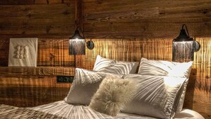 Una camera da letto accogliente con una testiera in legno, un letto con lenzuola bianche, cuscini soffici e due lampade a parete.