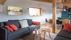 Un soggiorno moderno con un divano grigio, un tavolino rotondo e un soffitto in legno.