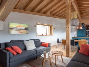 A modern living room with a grey sofa, a small round table, and a wooden ceiling. - Family chalet with jacuzzi, garage and fireplace in Les Gets (Les Gets)