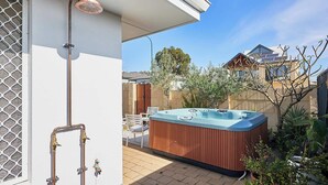 A hot tub in a backyard with a patio chair and a decorative lamp. - Sunny Scarborough Stay-Freshly Renovated! (Scarborough)