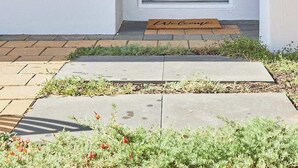 A blue door with a doormat, a wall-mounted decorative item, and a stone pathway leading to the entrance. - Sunny Scarborough Stay-Freshly Renovated! (Scarborough)