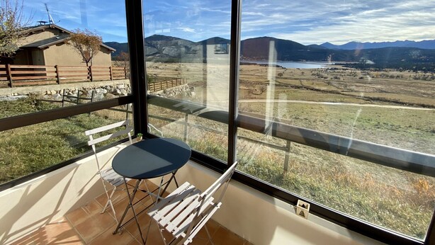 Un balcon avec une table et des chaises, une vue sur un paysage montagneux et un bâtiment doté d’un toit en pente.