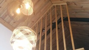 Ein Zimmer mit freiliegenden Holzbalken, einer geneigten Decke und zwei Hängeleuchten.