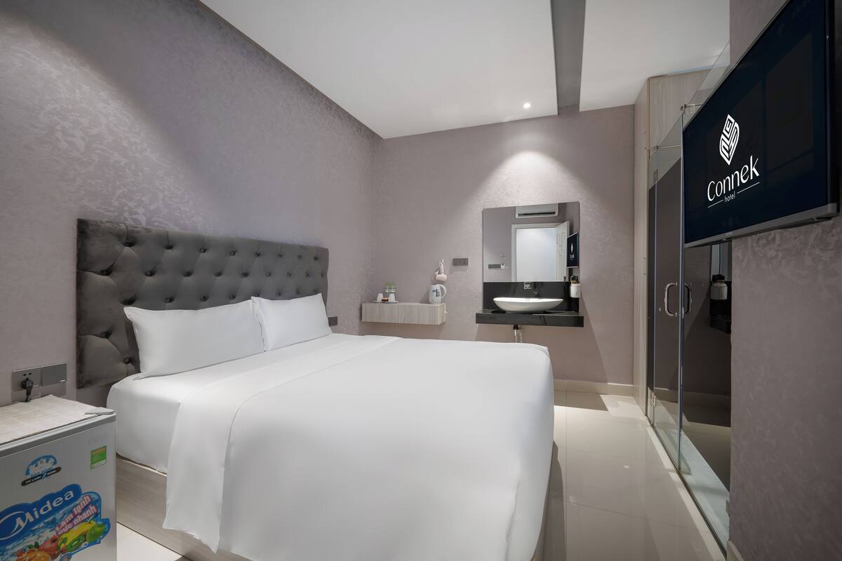 Une chambre d’hôtel moderne avec un grand lit, une coiffeuse avec un miroir et un espace douche.