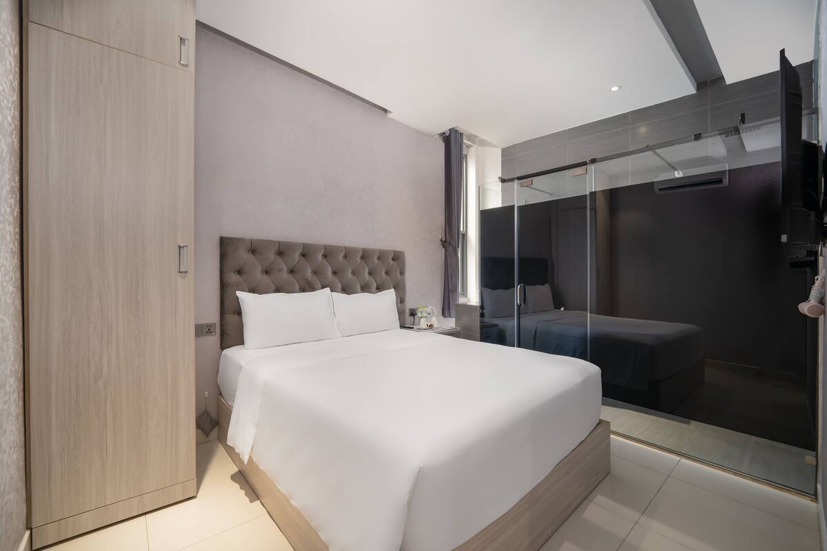 Une chambre moderne avec un grand lit, une armoire et une cabine de douche en verre.