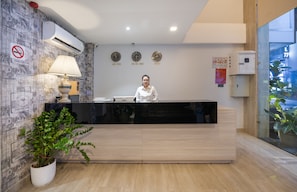 A reception desk with a modern design, a potted plant, and a wall clock. - Mari Queen Hotel - Bui Thi Xuan (Ho Chi Minh City)