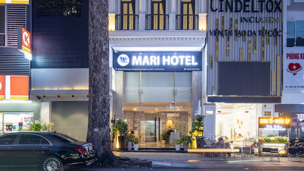 A hotel with a prominent sign, a tree in front, and adjacent buildings.
