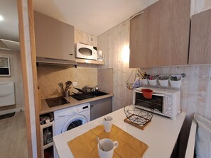 A compact kitchen with a microwave, oven, and washing machine. - Cozy studio 3 ppl, pets ok, parking - Les Deux Alpes (Les Deux Alpes)