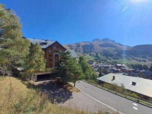 A mountain lodge with a prominent building, a paved road, and a view of a valley with scattered houses.