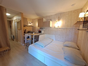 A compact room with a bed, a kitchenette, and a small dining area.