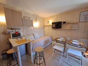 A compact room with a bed, a small kitchenette, a dining area with a table and chairs, a TV mounted on the wall, and a wooden floor. - Cozy studio 3 ppl, pets ok, parking - Les Deux Alpes (Les Deux Alpes)