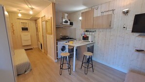 A compact kitchen with a washing machine, a microwave, and a small dining area with stools. - Cozy studio 3 ppl, pets ok, parking - Les Deux Alpes (Les Deux Alpes)