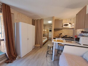 Ein kleines Zimmer mit Küchenzeile, einem Bett und einer Essecke.