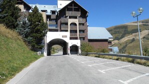 A multi-story building with a prominent entrance, likely a hotel or lodge, featuring balconies and a mountain backdrop. - Cozy studio 3 ppl, pets ok, parking - Les Deux Alpes (Les Deux Alpes)
