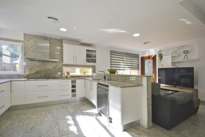 A modern kitchen with white cabinets, granite countertops, and a built-in dishwasher.