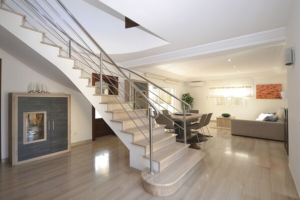 A modern interior with a curved staircase, a dining area, and a living space.