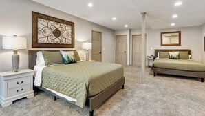 A bedroom with two beds, a nightstand, a lamp, and a decorative wall piece.