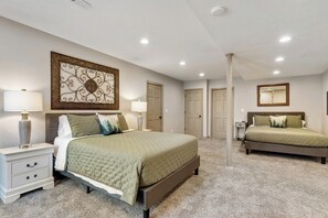A bedroom with two beds, a nightstand, a lamp, and a decorative wall piece.