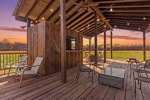 A wooden deck with outdoor furniture and a covered area with string lights.
