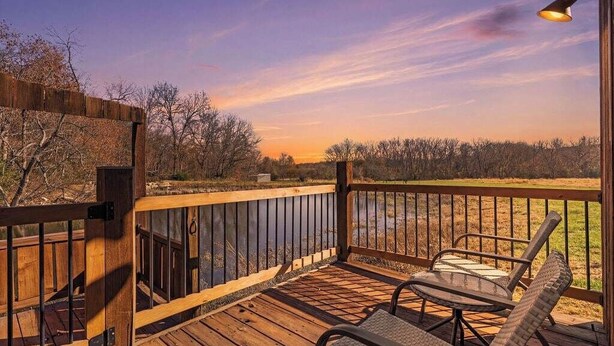 A wooden deck with a railing, a table, and two chairs.