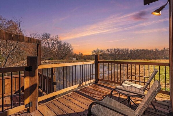 A wooden deck with a railing, a table, and two chairs.