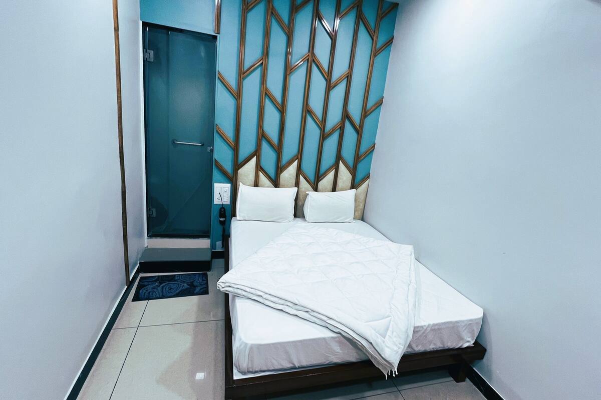 A hotel room with a bed, a door, and a wall with a geometric pattern.