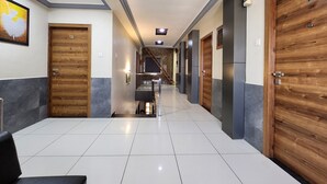 Ein Hotelgang mit Holztüren, einer Treppe und einem Empfangsbereich mit einer Sitzbank.