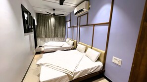 A hotel room with two beds, a ceiling fan, an air conditioning unit, and a TV mounted on the wall. - Hotel Vandana Palace (Wadhwan)