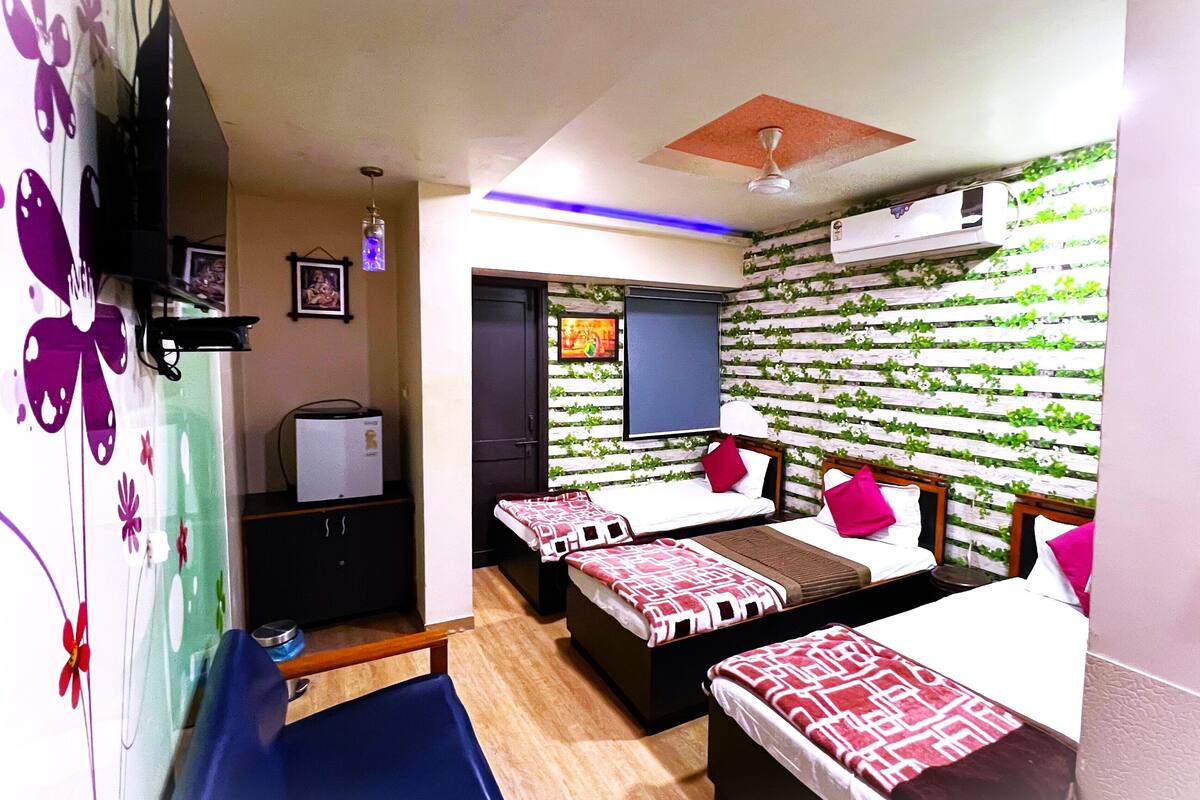 A hotel room with two beds, a wardrobe, a ceiling fan, and a wall with a green leafy pattern.