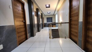 Ein Flur mit Fliesenboden, Holztüren und einer Treppe mit Handlauf.