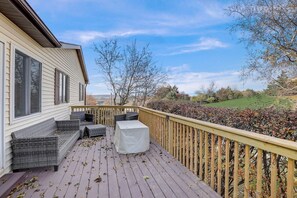 A deck with outdoor furniture, a covered table, and a view of a green landscape. - Draper Vacation Home - Families & Friends Welcome (Baraboo)