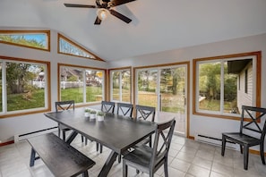 A sunroom with a large table and chairs, large windows, and a ceiling fan. - Draper Vacation Home - Families & Friends Welcome (Baraboo)