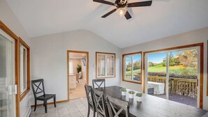 A dining area with a table and chairs, a ceiling fan, and large windows with a view of a garden. - Draper Vacation Home - Families & Friends Welcome (Baraboo)