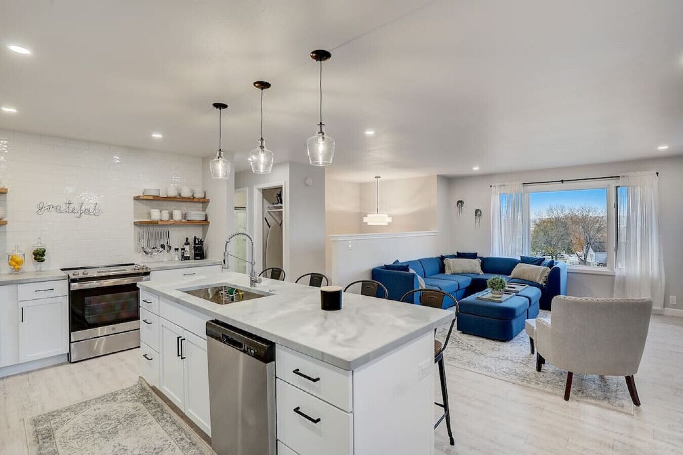 A modern kitchen with a central island, built-in oven, and stainless steel dishwasher.