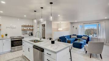 A modern kitchen with a central island, built-in oven, and stainless steel dishwasher.
