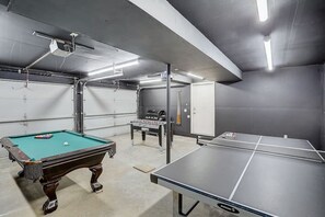 Una sala de juegos con mesa de billar, mesa de futbolín y mesa de ping pong.