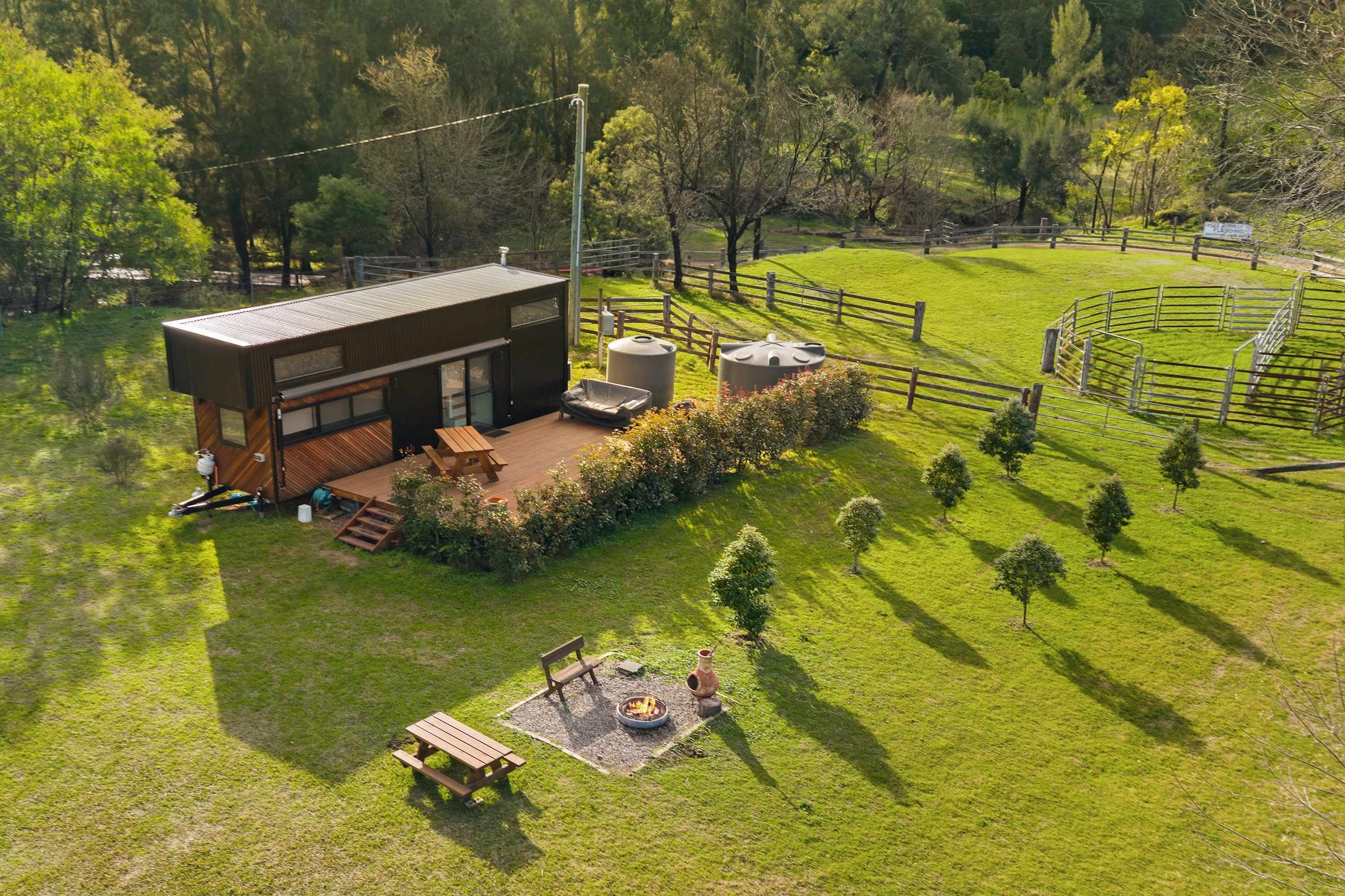 Ein modernes Haus mit Terrasse, Feuerstelle und umzäunter Garten.