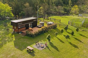 A modern house with a deck, a fire pit, and a fenced garden.