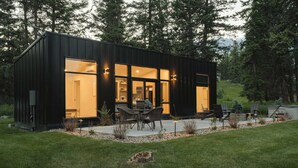 A modern, single-story building with large windows, outdoor seating, and a well-maintained lawn. - Teakettle-Modern-Close To Glacier, Skiing (Columbia Falls)