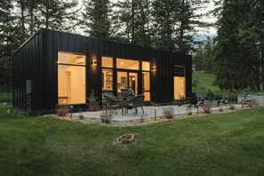 A modern, single-story building with large windows, outdoor seating, and a well-maintained lawn. - Teakettle-Modern-Close To Glacier, Skiing (Columbia Falls)