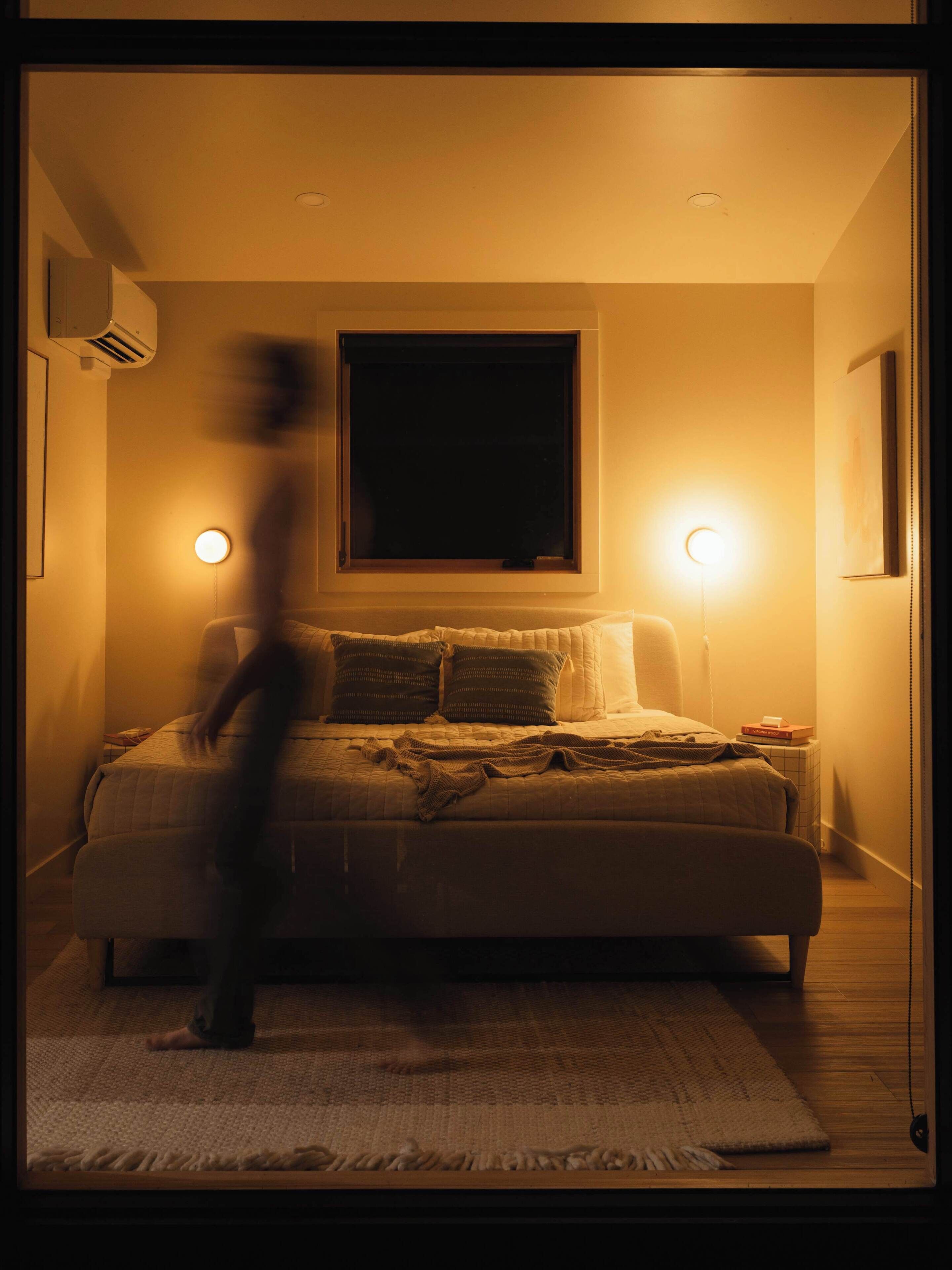 A bedroom with a bed, bedside lamps, and a window.