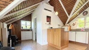 A spacious kitchen with wooden cabinets, a central island, and a dining area with a black chair. - "Gretta" - 400m from the sea by Interhome (Dannemare)