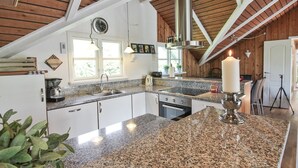 A kitchen with granite countertops, white cabinets, a stainless steel sink, and a large white candle on the island. - "Gretta" - 400m from the sea by Interhome (Dannemare)